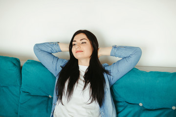 Young woman relaxing on a couch in living room. Home, comfort, dreaming and harmony
