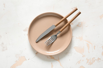 Clean plate and cutlery on light background