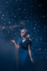Fototapeta na wymiar Young beautiful woman queen. blonde girl with fantasy mystic dragon. Carnival fairy tale character costume medieval dress style. Halloween image. Backdrop night winter blue snow fall blizzard