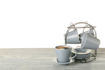 Holder with cups and saucers on table against white background