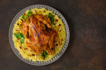 Kabsa - arabian dish made of long grain basmati rice, whole chicken, onion, spices: cardamom, saffron, cinnamon, bay leaves.  Decorated with almonds and raisins. Saudi Arabia food.