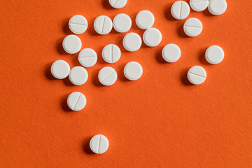 white pills on orange background. drugs isolated orange copy space. healthcare medicine concept, aspirin, antibiotics