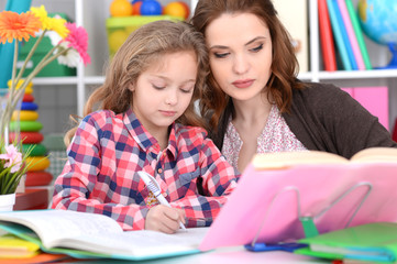 Cute little girl with her mother doing homework