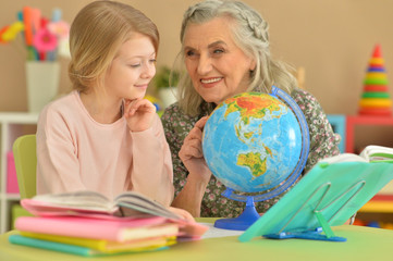 Close up portrait of grandmother with cute little girl doing homework