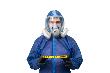 a man in a protective blue suit and a protective mask holds a sign stay at home