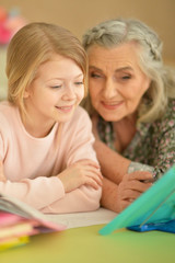 Fototapeta na wymiar Close up portrait of grandmother with cute little girl doing homework