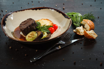 Slice of pork with grilled vegetables on a plate.