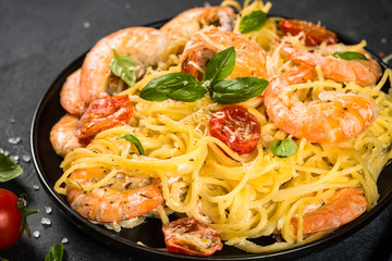 Pasta seafood with shrimp on black table.