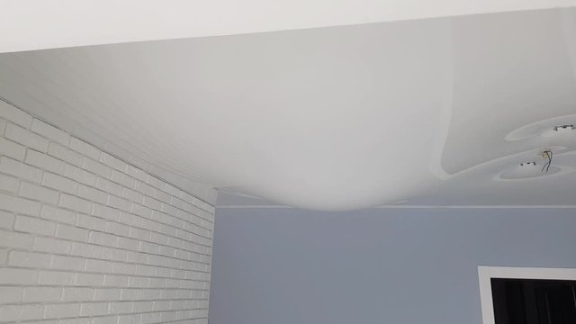 Stretch ceiling in the room filled with water. Flood, water leakage from the ceiling in the apartment.