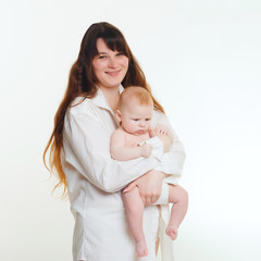 young brunette mom with long hair and a white shirt holds a newborn son. A 4 month old baby in her arms. Isolate