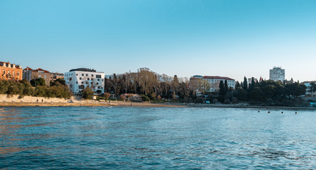 Popular beach of Bacvice in Split, Croatia. Early morning sunrise , empty beach on a cold day. Beautiful blue sky and ocean. Panorama wide shot with people walking their dogs