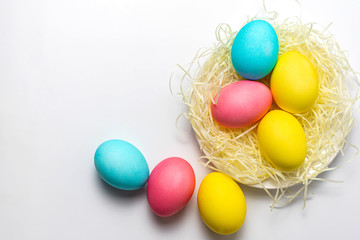 Colored Easter eggs in nest isolated on white background. Happy Easter card, copy space, top view