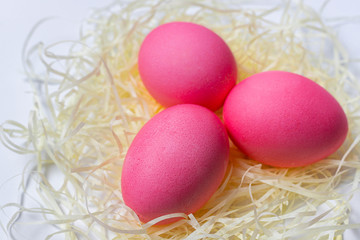 Fototapeta na wymiar Pink Easter eggs in nest isolated on white background. Happy Easter card, close-up