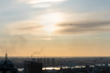 Airplane far in the sky over the city at sunset.