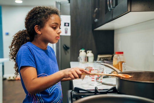 Girl cooking meal at stove in home kitchen