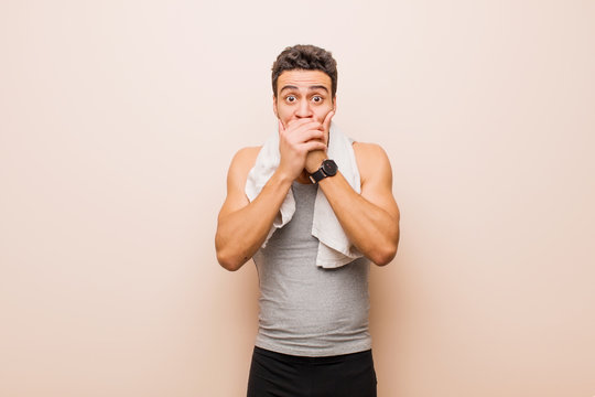 young arabian man covering mouth with hands with a shocked, surprised expression, keeping a secret or saying oops. sport concept