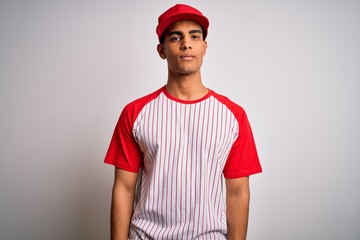 Young handsome african american sportsman wearing striped baseball t-shirt and cap Relaxed with serious expression on face. Simple and natural looking at the camera.