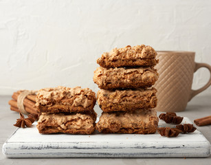 stack of baked Krakow meringue cookies on a wooden board and a white ceramic cup with black coffee