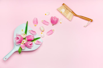 Shovel with floor brush and spring flowers on color background