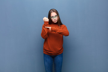 young blonde pretty girl looking impatient and angry, pointing at watch, asking for punctuality,...