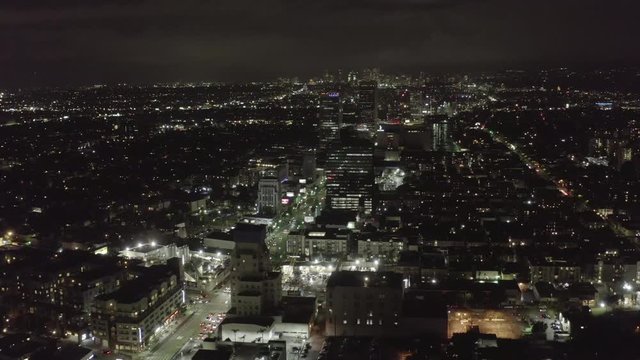 AERIAL: Over Dark Hollywood Los Angeles at Night with view on Skyline and City Lights 