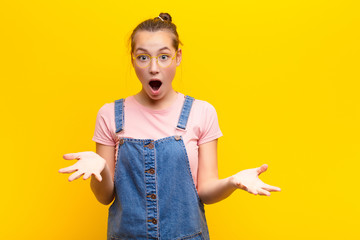 young blonde pretty girl feeling extremely shocked and surprised, anxious and panicking, with a...