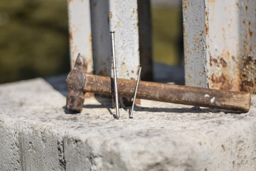 Old hammer and nails close up. Hand tool is on concrete. Hand tool photographed from the side