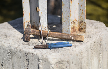 Hammer, nails and pliers with blue plastic handles close up. Two hand tools are on concrete. Hand tools photographed from the side