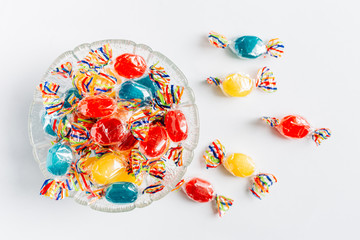Bowl full with mix hard wrapped candies isolated on white background.