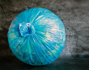 Globe in a plastic garbage bag close-up on a gray textured background. Concept: nature protection,...