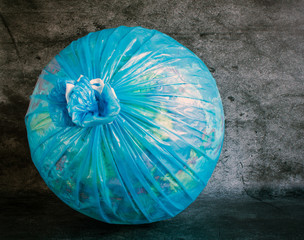 Globe in a plastic garbage bag close-up on a gray textured background. Concept: nature protection, environmental problems in the world.