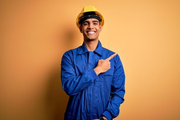 Young handsome african american worker man wearing blue uniform and security helmet cheerful with a...