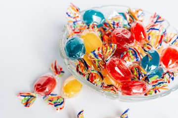 Bowl full with mix hard wrapped candies isolated on white background.