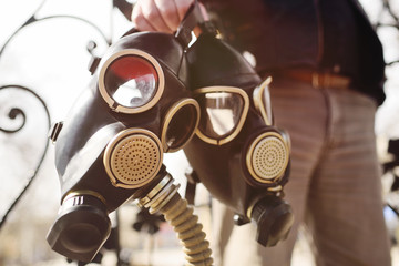 a man is holding two black gas masks in close-up. Radiation, nuclear explosion, Apocalypse,...