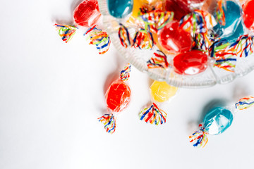 Fototapeta na wymiar Bowl full with mix hard wrapped candies isolated on white background.