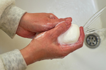 Fototapeta premium Hands holding a white soap while washing