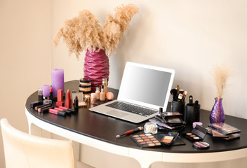 Set of decorative cosmetics and laptop on table of makeup artist in salon