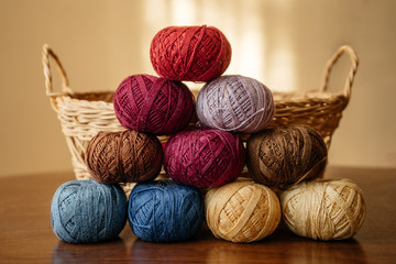 Multi-colored balls of wool yarn folded into a pyramid on a wooden table