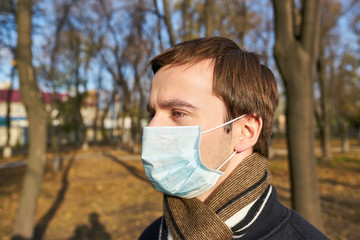 Closeup portrait of a young guy in a disposable medical mask. Pandemic. Coronavirus. Quarantine. The young man in the mask.