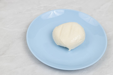 Mozarella cheese served on the blue plate above white marble table