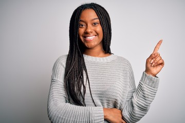 Young african american woman standing casual and cool over grey isolated background with a big smile on face, pointing with hand and finger to the side looking at the camera.