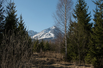 View on a rocky alpine mountain covered in melting snow on sunny spring day