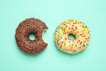 Delicious glazed donuts on turquoise background, flat lay