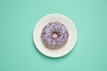 Delicious glazed donut on turquoise background, top view