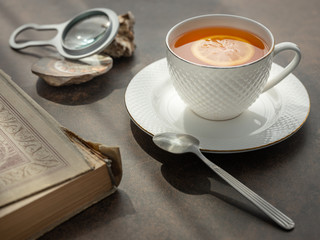 cup of tea with magnifier glass and old book on the table