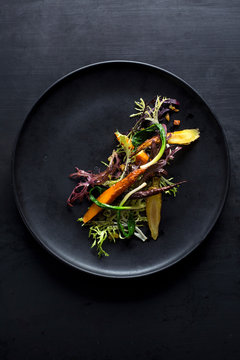 Overhead view of roasted carrots and frisee salad served on plate