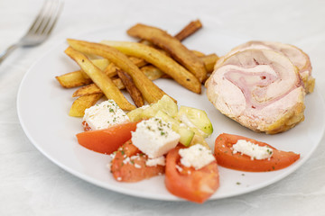 Served rolled chicken with tomato salad with mozarella and french fries