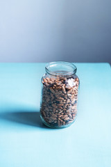Pinto beans in a glass jar view on a light background with empty space on the left. Minimalist style vertical shot