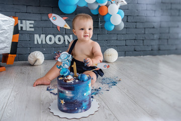 Fototapeta premium Little boy celebrates his first birthday. Space design with a robot and stars, many colorful balloons.