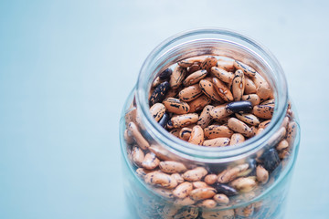 Pinto beans in a glass jar view on a light background with empty space on the left. Minimalist...